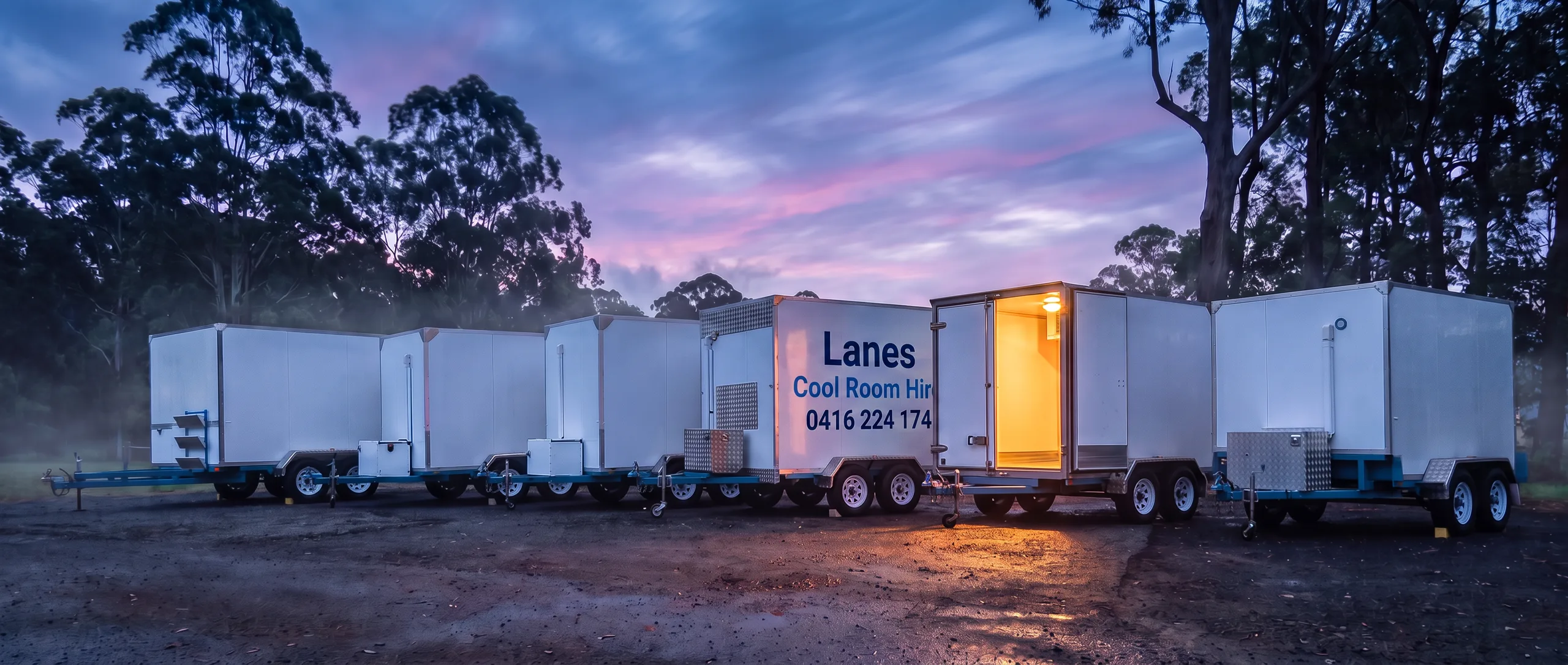Fleet of Lanes coolroom trailers lined up at dusk with one door open and glowing
